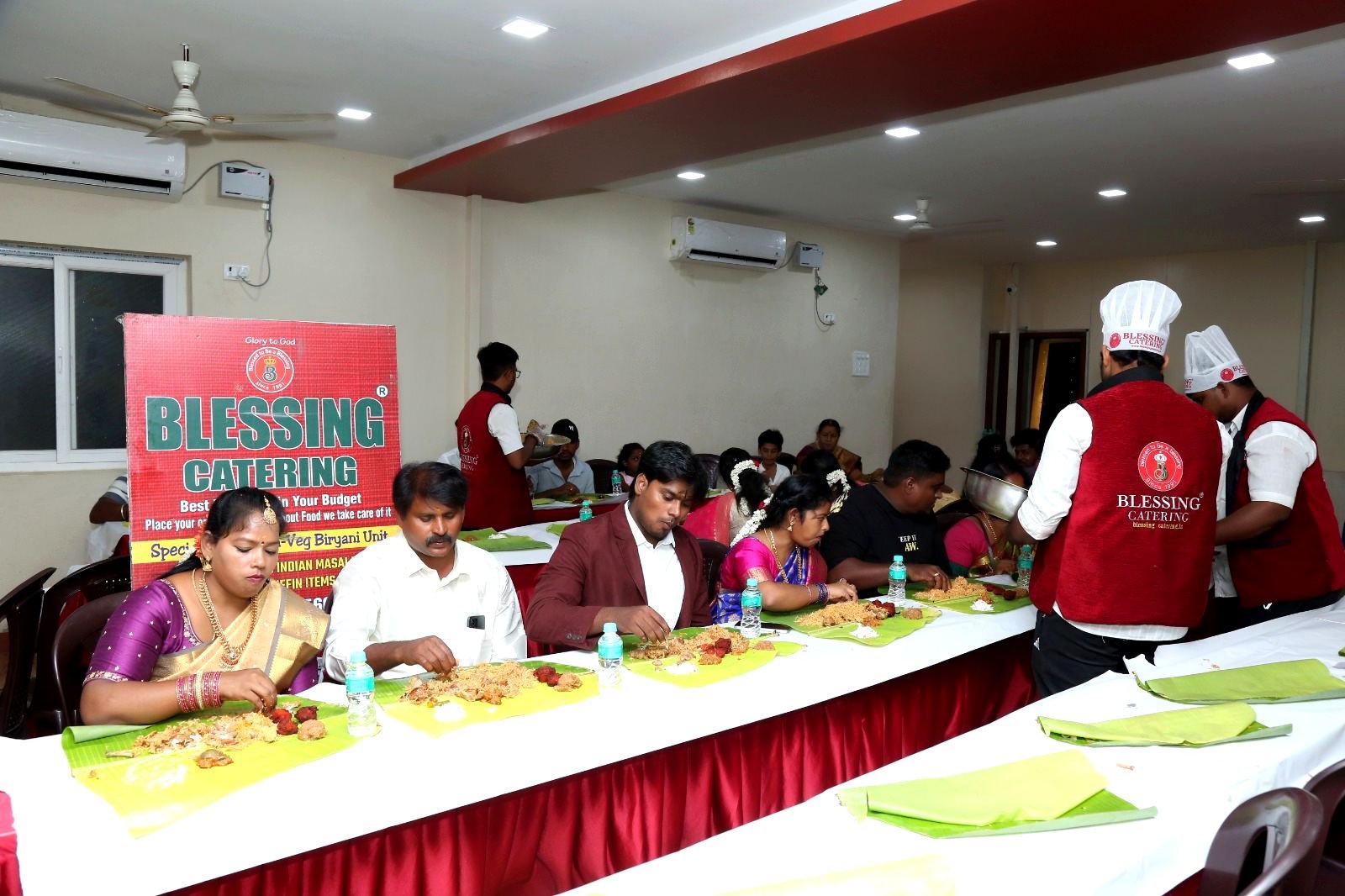 Guests seated at long tables in the dining hall, served on banana leaves